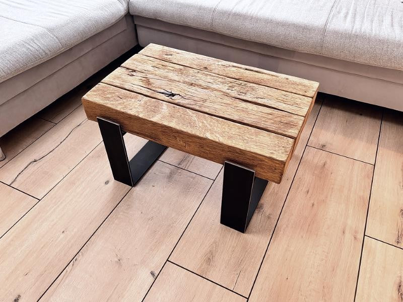 Couchtisch aus antiker Eiche mit dunklen Stahlkufen neben einem Sofa, schräg von oben
