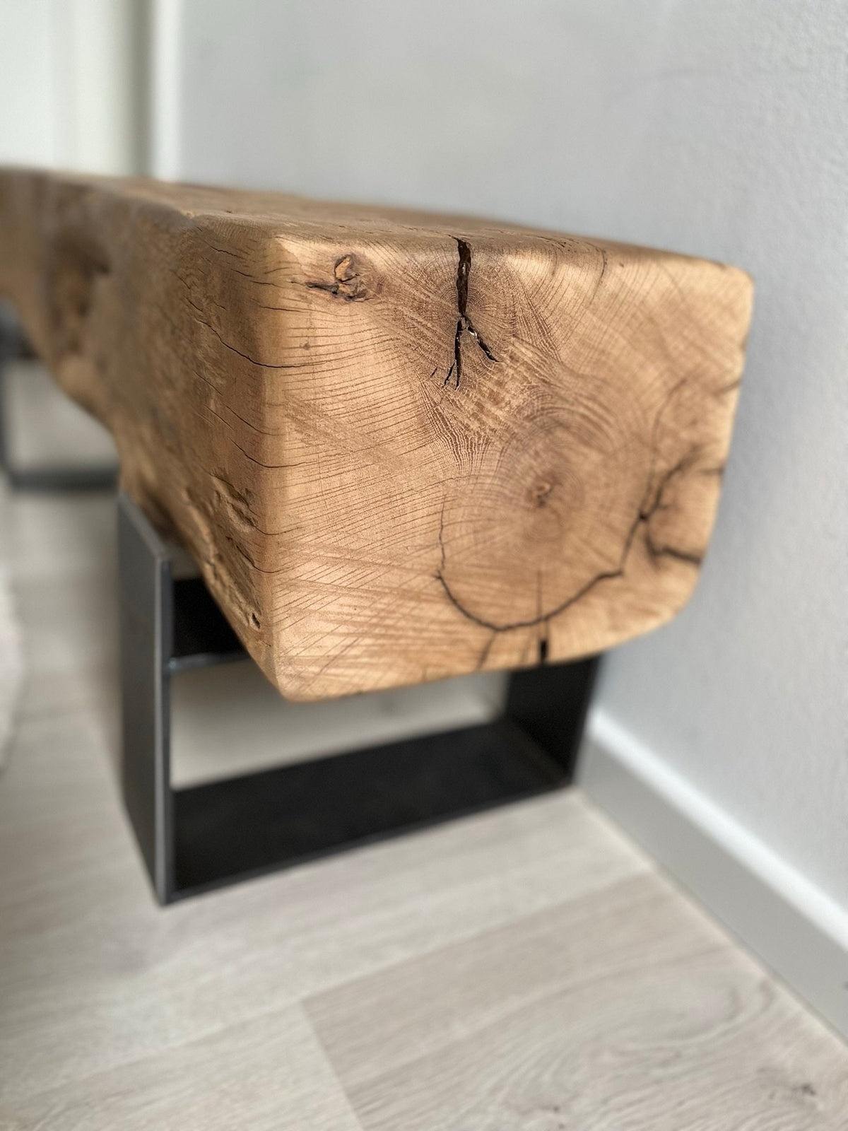 Stirnseite des antiken Eichenbalkens – sichtbare Jahresringe und natürliche Risse