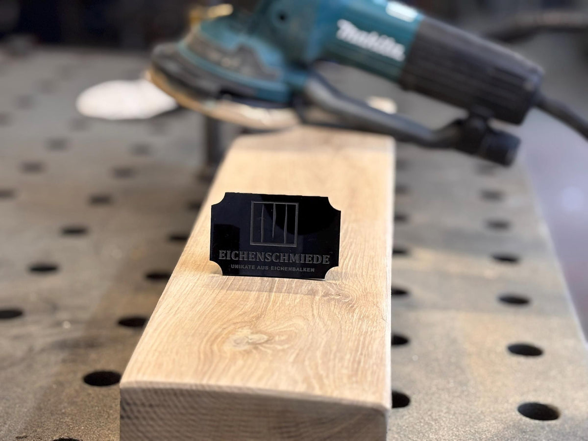 Lasergravur des Eichenschmiede-Logos auf einem Eichenholzstück in der Werkstatt