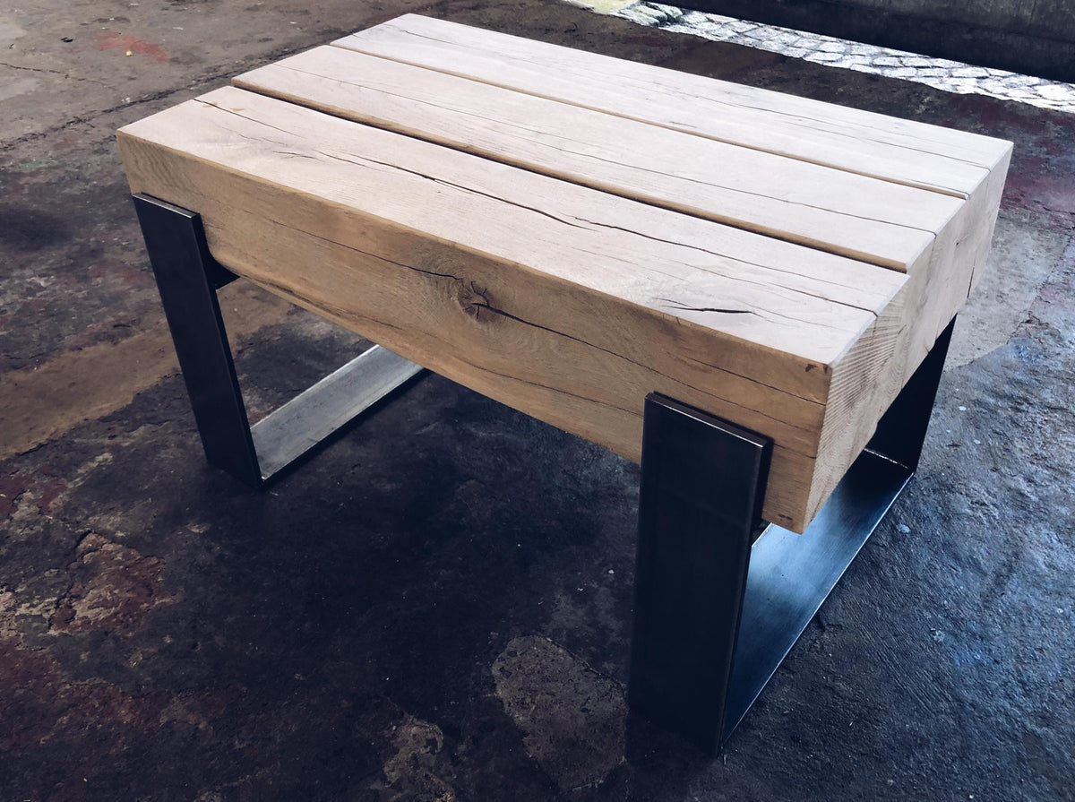 Massiver Couchtisch aus antiker Eiche mit sichtbar bearbeiteten Balkenenden und Stahlgestell